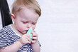 A defocused infant uses a nasal aspirator into the nose, sucking out the mucus. Cleansing snot in a child. Copy space - concept of health, colds, immunity, prevention, parental love, cure