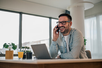 Cheerful distracted business professional talking on mobile phone at office