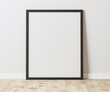 Blank Vertical black frame on wooden floor with white wall, 4:5 ratio - 40x50 cm, 16 x 20 inches, poster frame mock up, 3d rendering