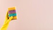 Hand in yellow glove holds sponges stack to wash dishes. Banner. Copy space