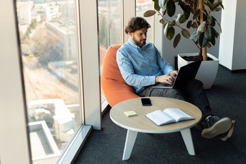 Aufkleber - Businessman using laptop sitting on bean bag in office
