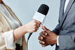 © Seventyfour - Side view closeup of young woman holding microphone while interviewing business expert
