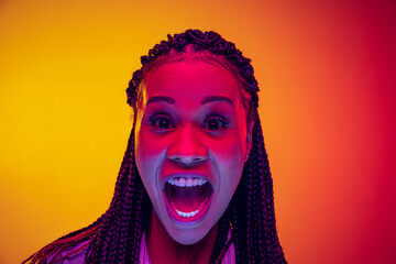 Wall Mural - Closeup portrait of shouting isolated on gradient yellow pink background in neon light. Concept of beauty, art, fashion, youth and emotions