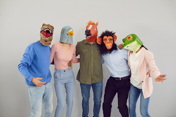 Portrait of cool eccentric diverse people in animal masks isolated on grey background hug show unity. Smiling funny friends in crazy headwear have fun together enjoy relax or leisure time.