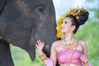 © somchairakin - Asian Woman with traditional thai dress look at her cute elephant, relationship between people and animals.