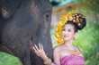 © somchairakin - Asian Woman with traditional thai dress smile with her cute elephant, relationship between people and animals.