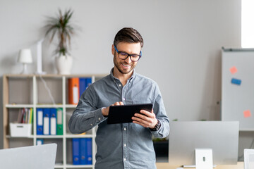 Aufkleber - Portrait of cheerful mature businessman using computer tablet in office, looking at screen and smiling, copy space