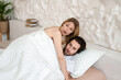 Shocked young lovers being caught while having extramarital sex in bed. Adultery, infidelity, having affair concept
