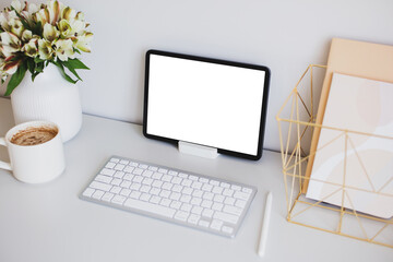 Fototapete - Stylish feminine workspace with graphic designer tablet mockup, keyboard, pen, cup of coffee, office stationery, vase of flowers.