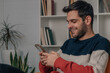 © carballo - young man at home looking at mobile phone