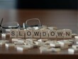 slowdown word or concept represented by wooden letter tiles on a wooden table with glasses and a book