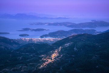 Wall Mural - small village on the mountain and city on the sea cost at night. aerial view. landscape with city li