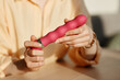 Minimal close up of young woman holding pink vibrator in hands while reviewing sex toys, copy space
