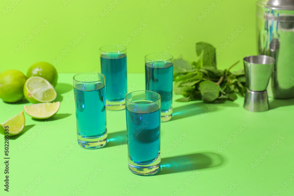 Shot cocktails, limes and mint on color background