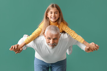 Wall Mural - Little girl with her grandfather on green background