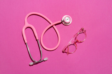 Wall Mural - Stylish eyeglasses with stethoscope on pink background