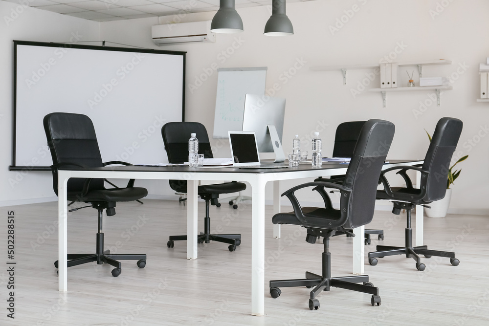 Modern interior of conference hall with big table and computers