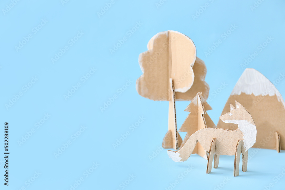 Handmade cardboard fox, mountain and trees on color background