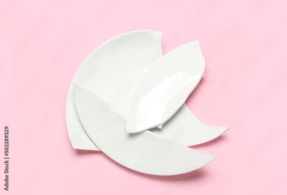 Broken ceramic plate on pink background