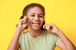 African-American teenage girl flossing teeth on yellow background