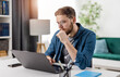 © MYDAYcontent - Concentrated young man sitting at table and checking programming code on laptop. Handsome bearded guy in glasses looking pensively on monitor.