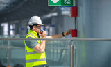 Fototapeta  - Engineer wearing safety unifrom and helmet under checking fire alarm emergency system in industry factory and exit door is factory security protection concept.