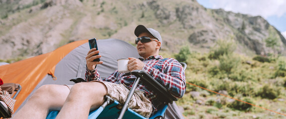 Wall Mural - Person using mobile phone and drinking coffee in the mountains