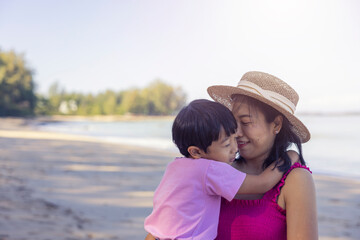 Asian boy and mom woman relaxing on tropical beach, they are njoy freedom and fresh air, wearing stylish hat and clothes. Happy smiling tourist in tropics in travel vacation