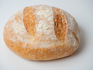 A close-up of a whole fresh crispy delicious round-shaped wheat bread on a white background. Insulated items, baking, side vew