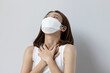 ill woman wearing face mask with flu, sore throat, air pollution allergy or long covid sickness