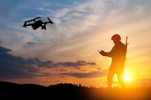 Silhouettes Of Soldiers Are Using Drone And Laptop Computer For Scouting During Military Operation Against The Backdrop Of A Sunset. Greeting Card For Veterans Day, Memorial Day, Independence Day.