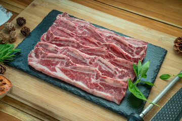 Wall Mural - Beef Short Ribs (Sliced) Bone-in on wooden background.Cross Cut Short Ribs beef on black plate. 