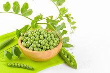 Fresh Organic Raw Green Peas In A Wooden Bowl With Peas Plants Leaves On A Napkin On White Background. Healthy Eating, Vegan And Vegetarian Legume Food, Raw Food And Detox Super Food, Bean Protein