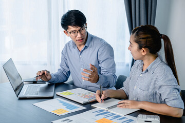 Leinwandbilder - Two business colleagues pointing business data on laptop and taking notes information on notebook while discussion