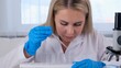 © Евгения Медведева - female research chemist scientist in a medical suit and protective gloves conducts research on samples with a micropipette and test tubes for working under a microscope in a laboratory.