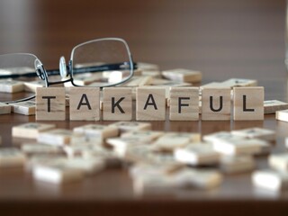 takaful word or concept represented by wooden letter tiles on a wooden table with glasses and a book