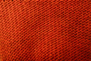 Knit red fabric texture, background or backdrop. Textile, scarf or sweater textured surface, back or wrong side. Warm accessories, clothing