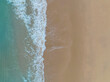 © SASITHORN - Aerial top view to tropical sandy beach and blue ocean. Top view of ocean waves reaching shore on sunn