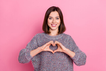 Sticker - Portrait of attractive cheerful girl showing heart symbol care isolated over pink pastel color background