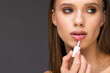 © F8  \ Suport Ukraine - Young woman make lips with lipstick on gray background