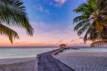 Amazing sunset panorama at Maldives. Luxury resort villas seascape with soft led lights under colorful sky. Beautiful twilight sky and colorful clouds. Beautiful beach background for vacation holiday