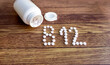 B 12 written with pills . Bottle and b12 pills on wooden background 