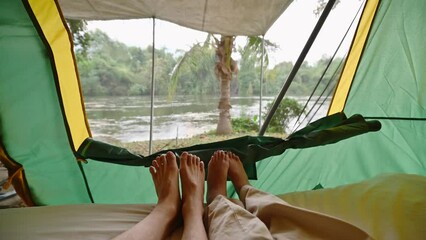 Wall Mural - Foots of young couple resting inside a tent and taking the riverside view