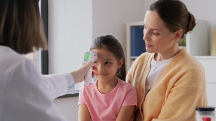 Sticker - medicine, healthcare and pediatry concept - mother with sick little daughter and doctor measuring temperature with infrared forehead thermometer at clinic