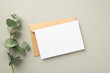 © ActionGP - Business concept. Top view photo of paper card craft paper envelope and eucalyptus sprig on pastel grey background with blank space