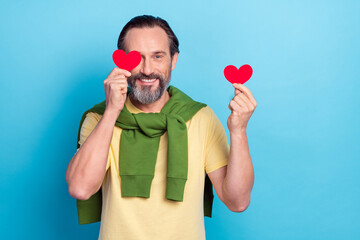 Sticker - Photo of cheerful person hold two small heart postcard cover eye isolated on blue color background