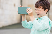Happy Boy Using Smartphone Near Blue Wall
