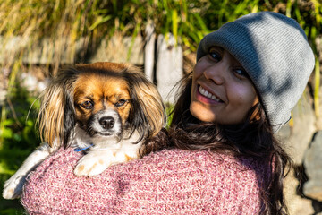 Wall Mural - Closeup shot of a Hispanic girl with a dog looking at the camera in New Zealand