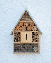 Closeup Shot Of A Wooden Insect Hotel With Different Sections On The Background Of A Blue Wall