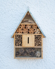 Sticker - Closeup shot of a wooden insect hotel with different sections on the background of a blue wall